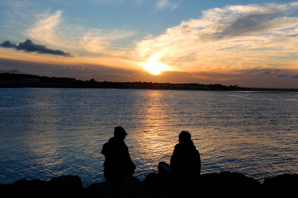 two people outside looking at large body of water