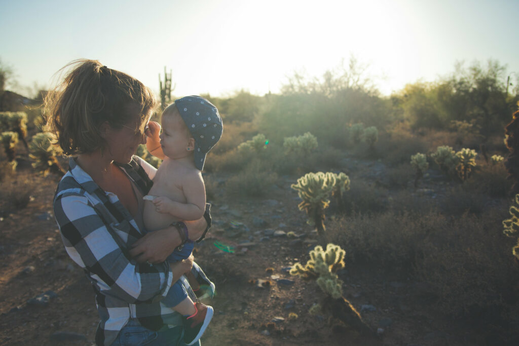 woman holding small child outside in desert landscape