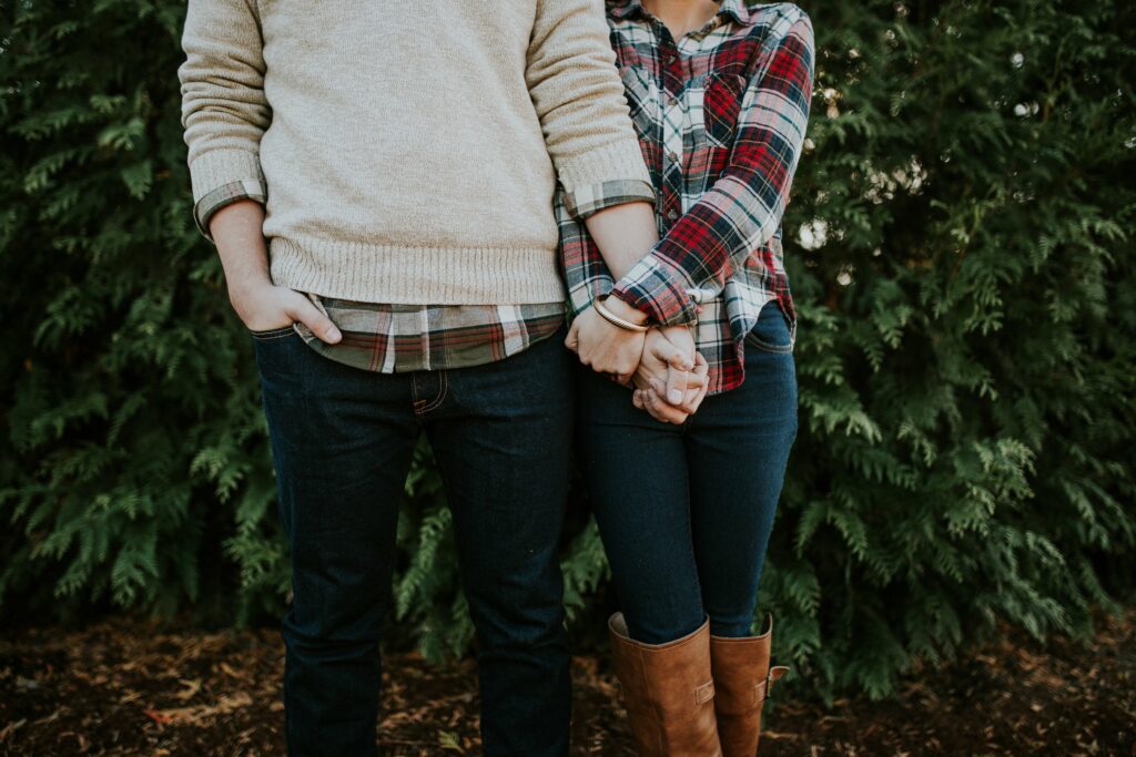 male and female holding hands outside wearing flannel shirts and jeans