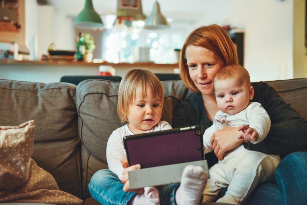 woman with two small children all looking at iPad