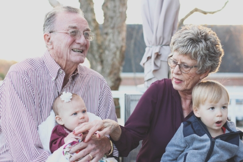 two grandparents holding male and female grandchild